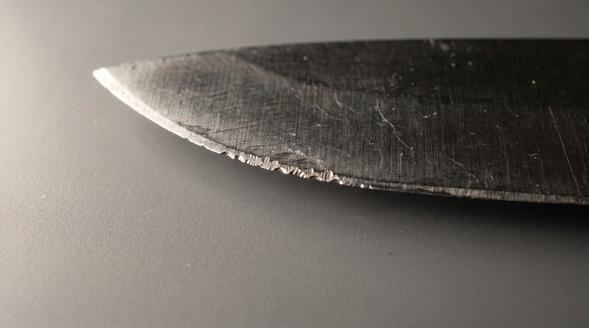 Close-up of a knife blade edge showing micro-chipping damage from glass cutting board use 