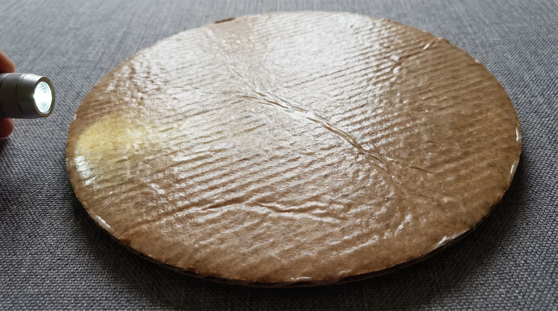 Close-up of frozen pizza cardboard disc underside showing grease-resistant coating surface 