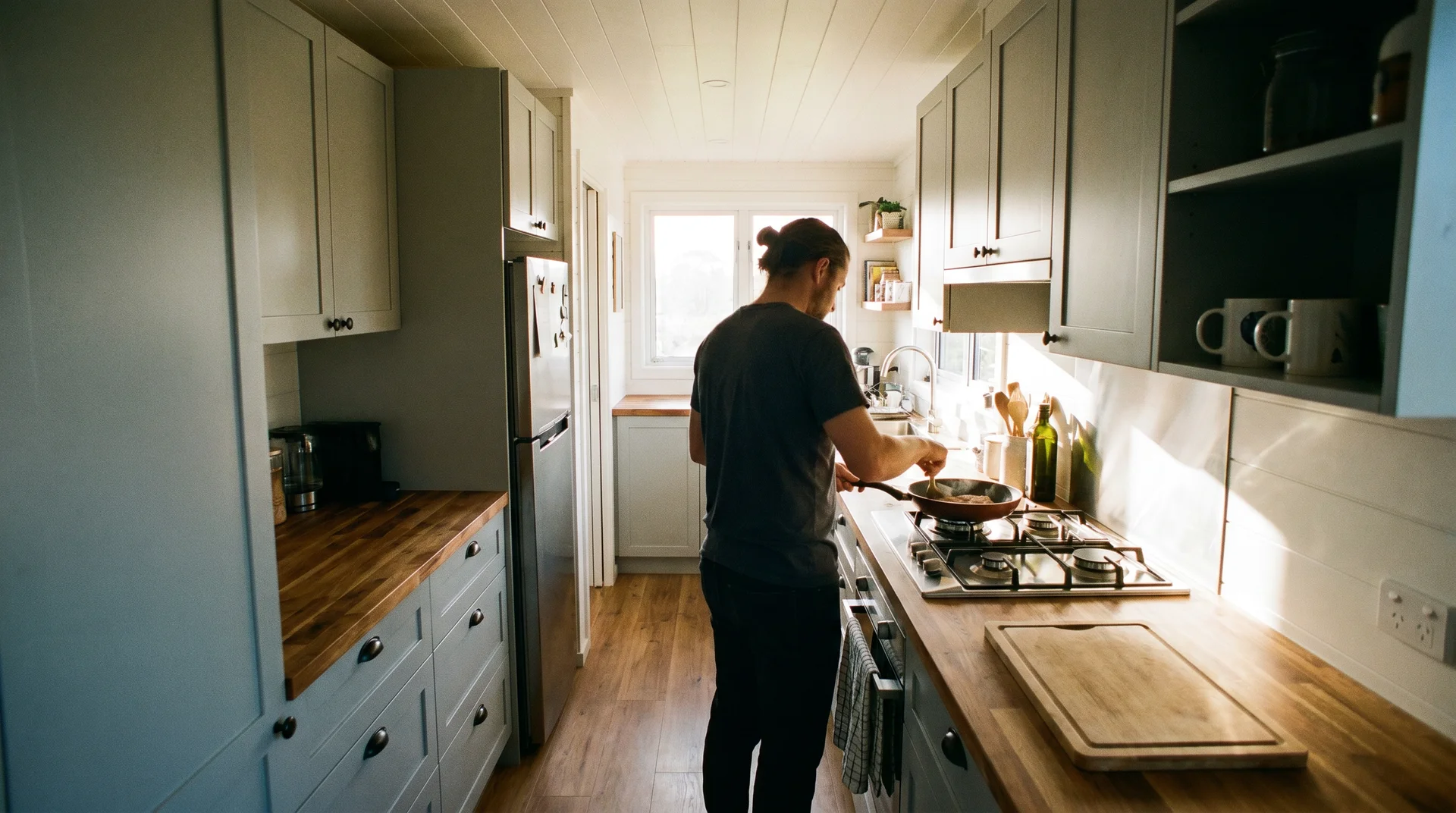 Galley tiny house kitchen showing sink, cooktop, and prep station in sequence with clear center aisle
