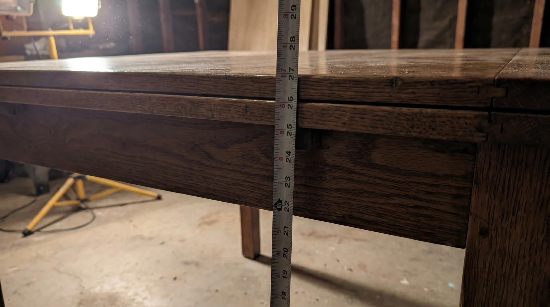 Measuring tape showing clearance from floor to dining table apron underside, not tabletop surface
