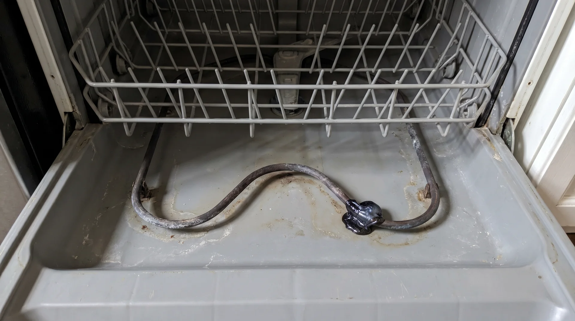 Melted plastic residue on dishwasher heating element coil visible from above
