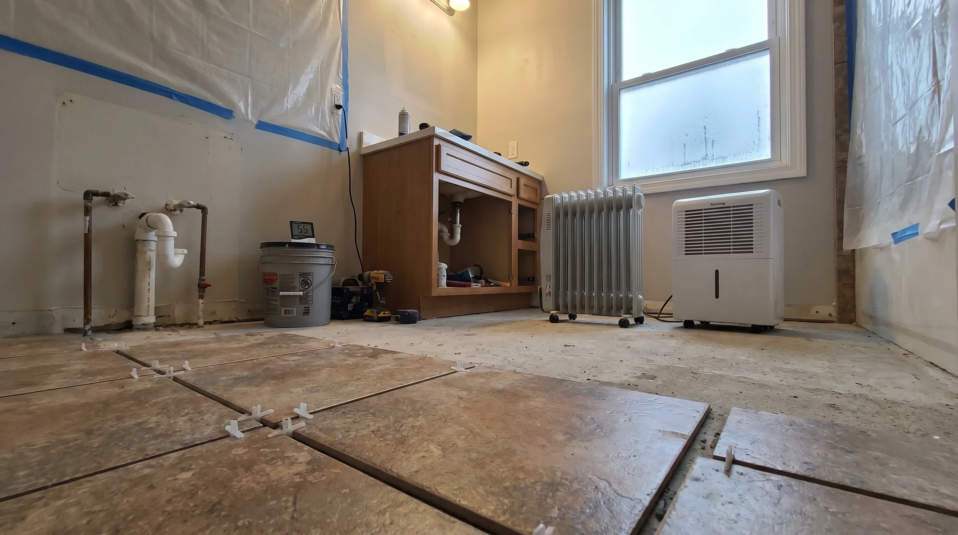 Small bathroom mid-renovation with ungrouted floor tile and visible environmental conditions