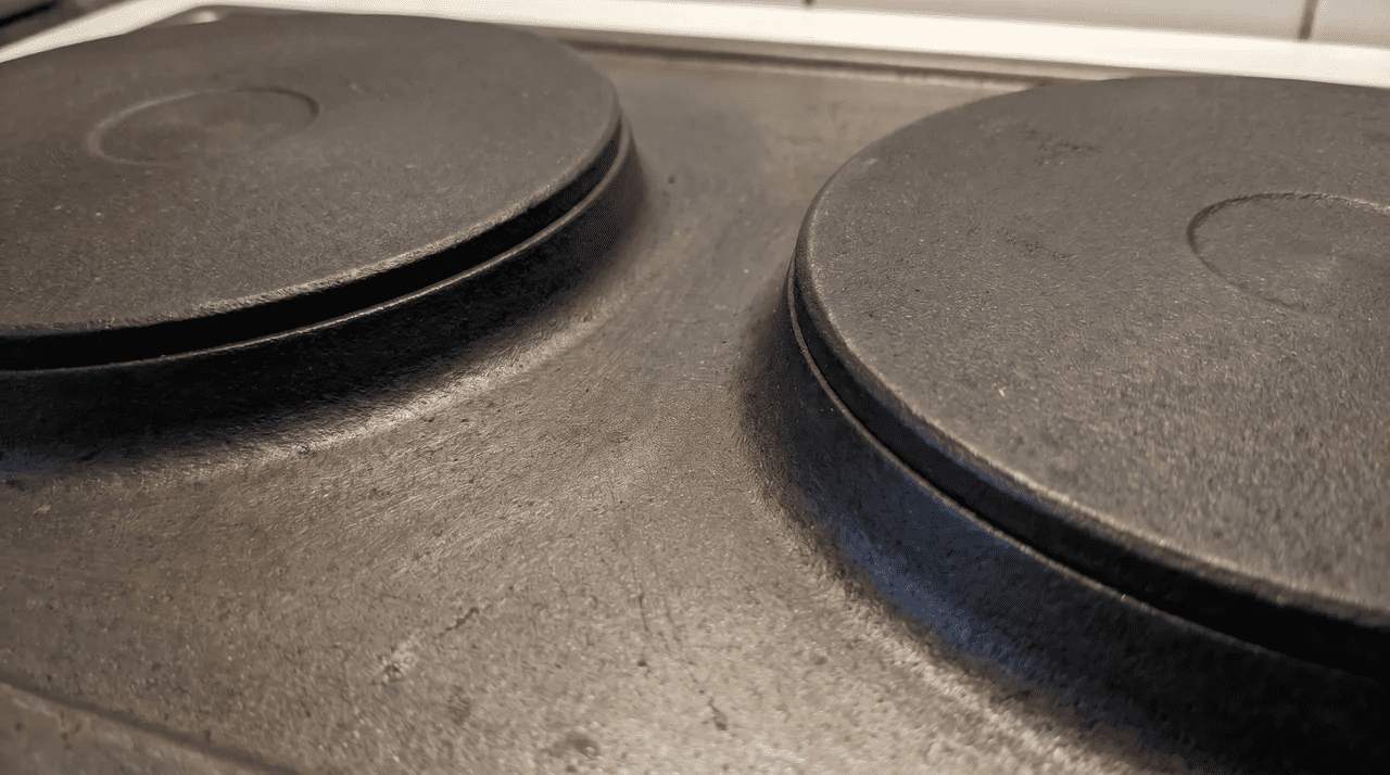 Two raised circular cast-iron solid plate discs on an electric hob surface, unlit