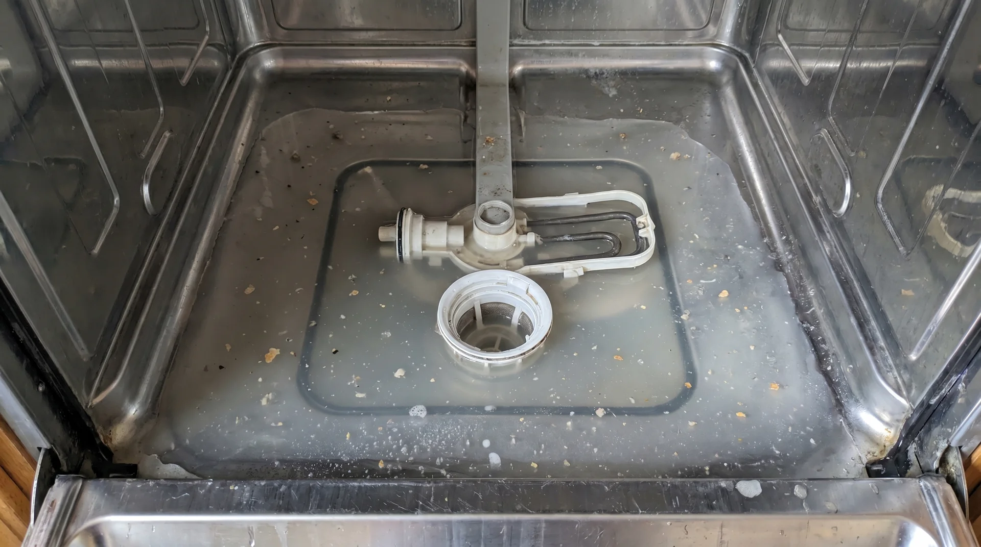 Standing water at the bottom of a dishwasher tub after a completed wash cycle
