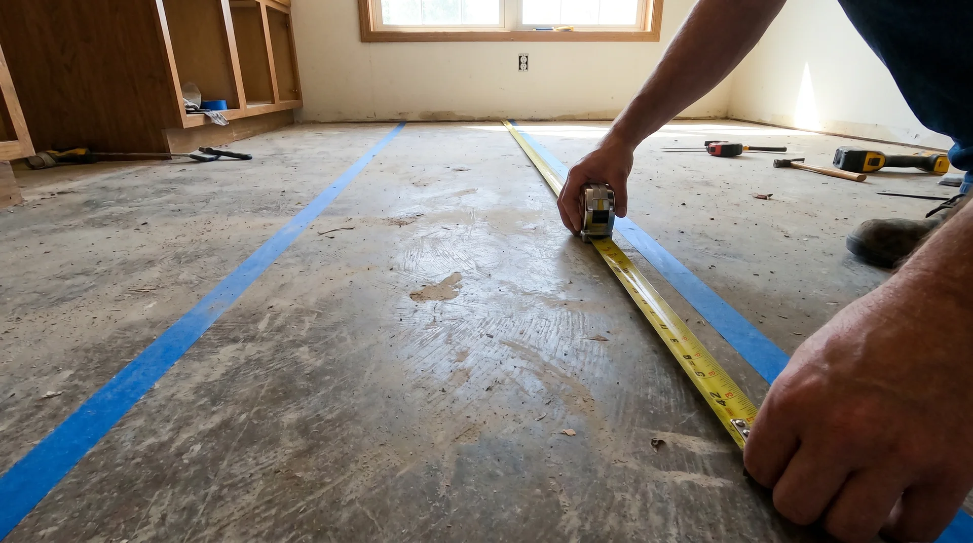 Tape measure stretched across a 42-inch kitchen aisle marked with painter's tape during a small kitchen layout mock-up