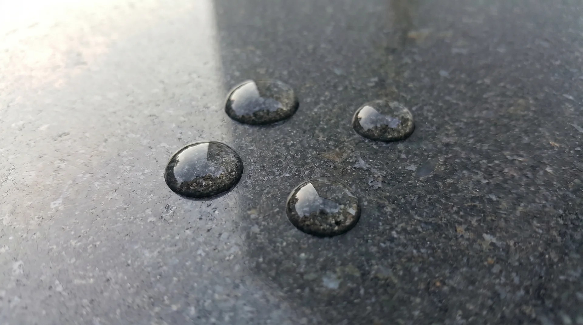 Water droplets beading on sealed granite countertop demonstrating intact sealer