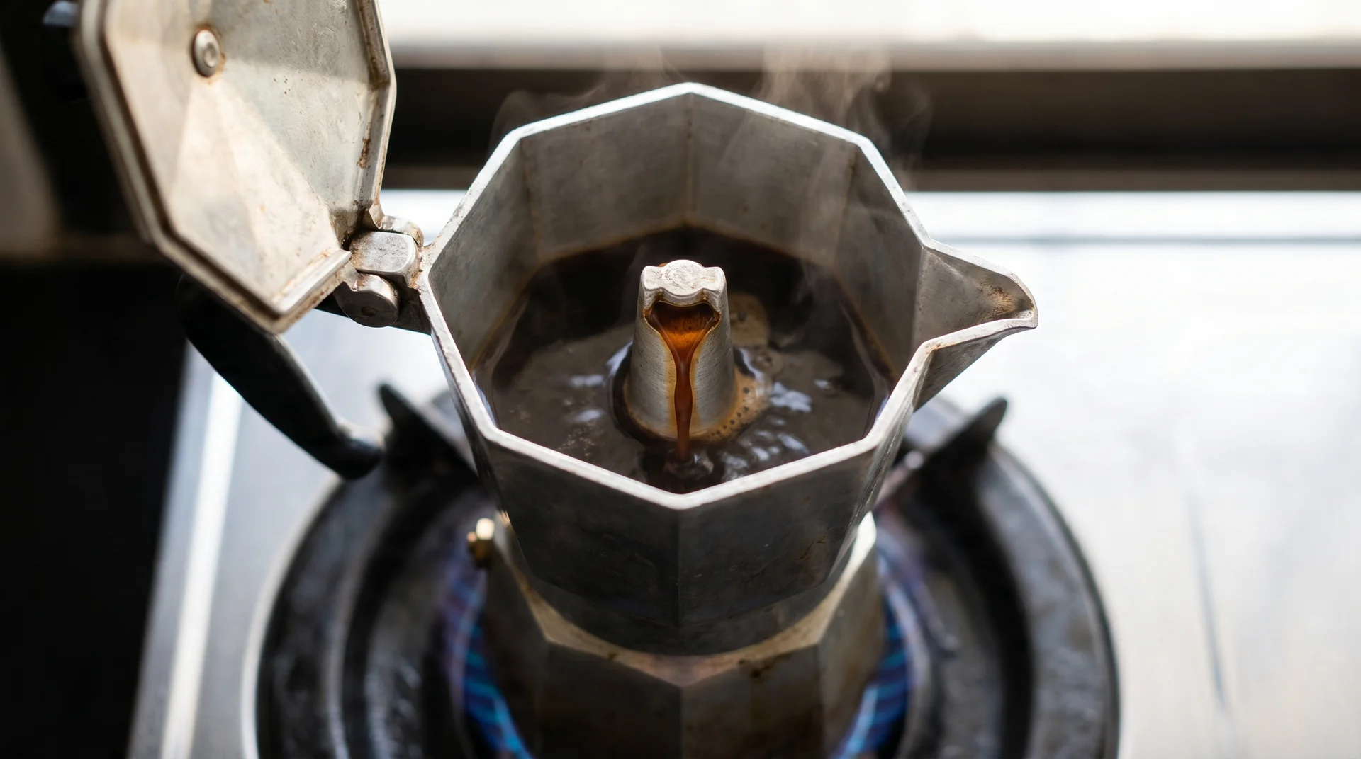3-cup moka pot mid-brew with coffee filling the upper chamber on a gas stove