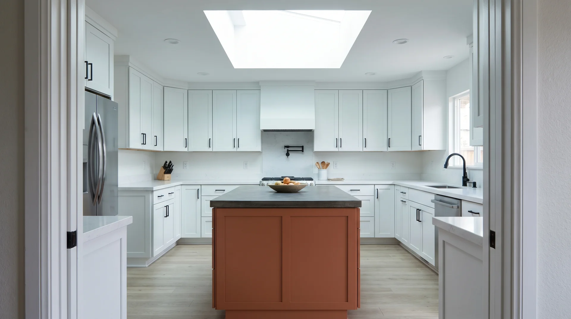 All-white kitchen perimeter with a terracotta island as the statement piece, matte black hardware, dark stone countertop