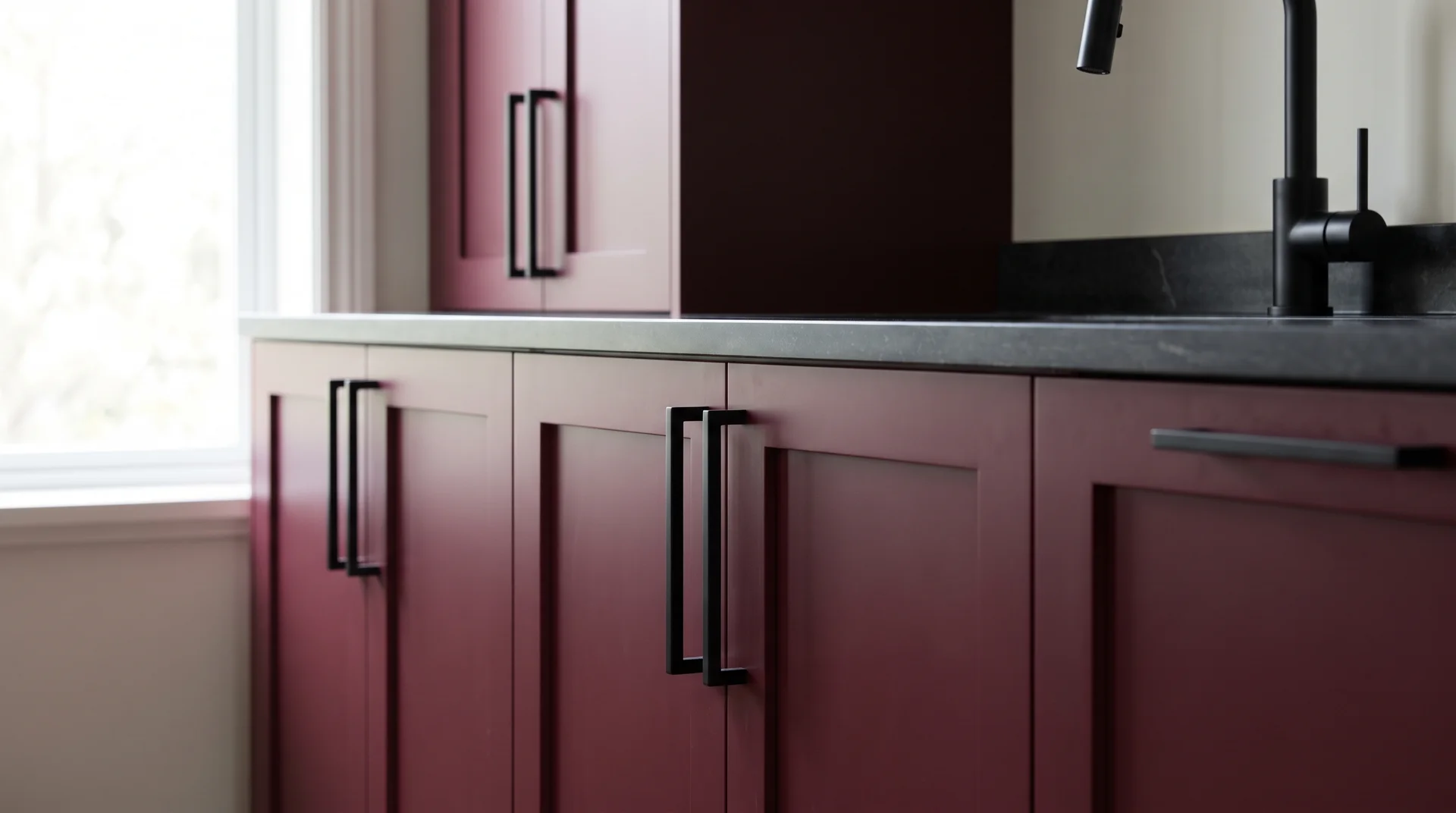 Burgundy Shaker cabinets with matte black bar pulls and a matte black faucet visible at the edge of frame
