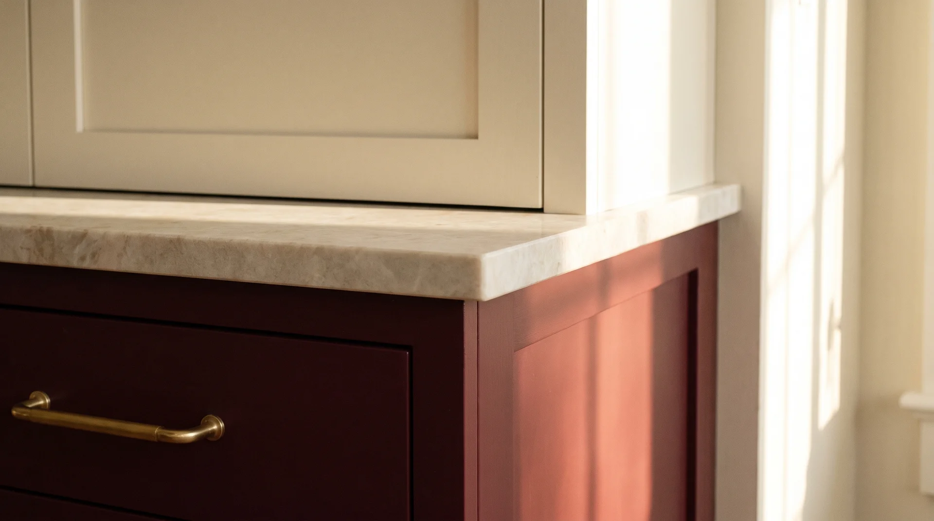 Burgundy lower cabinet beside warm white countertop and cream upper cabinet showing the resolved color pairing