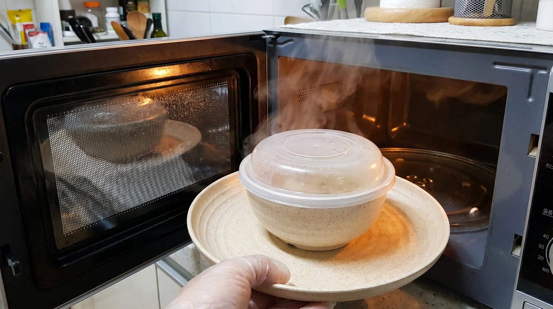 Covered food on a wheat straw plate inside a microwave showing steam buildup under the cover