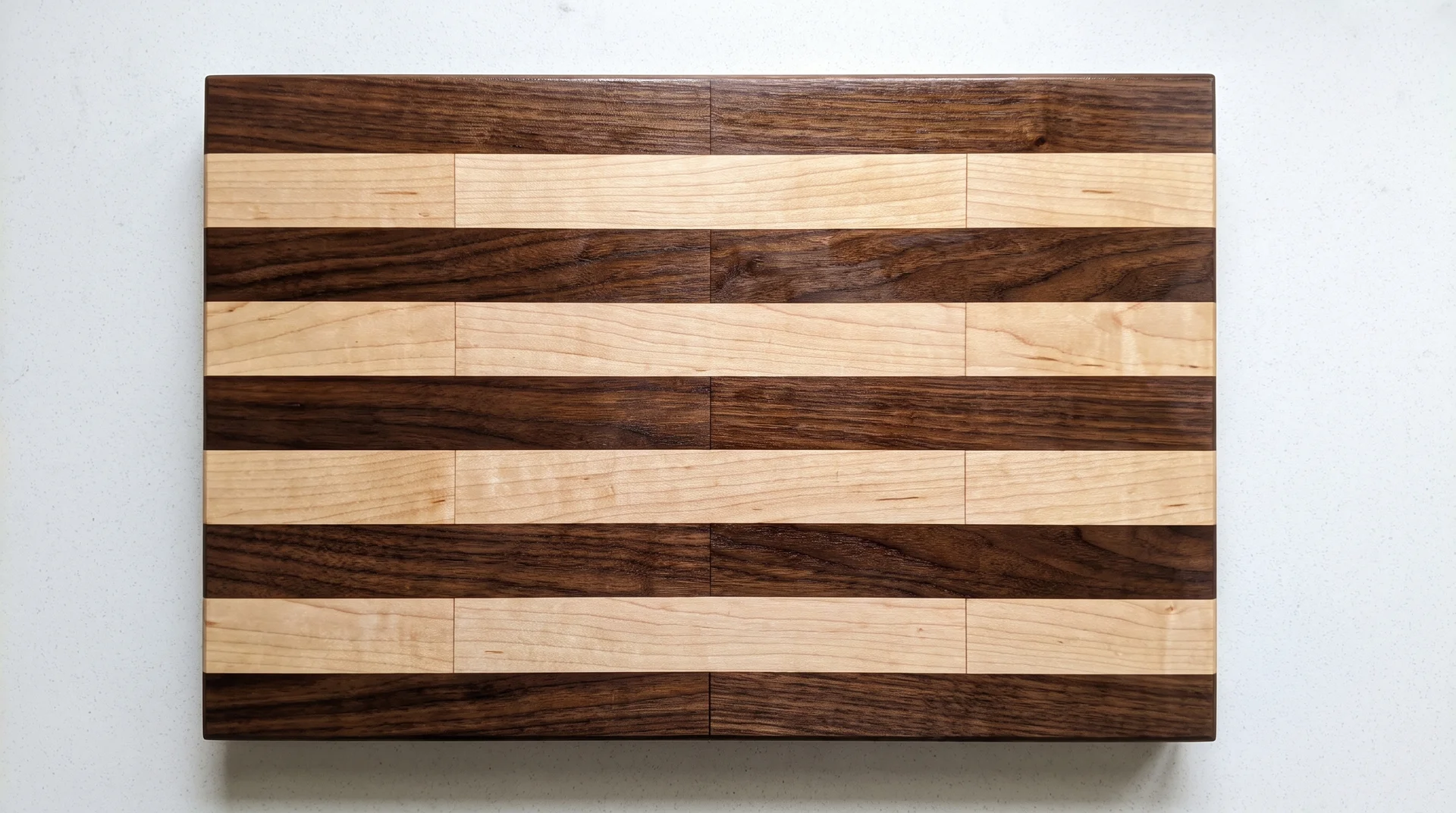 Face-grain brick layout cutting board with walnut and maple strips in horizontal offset brick pattern