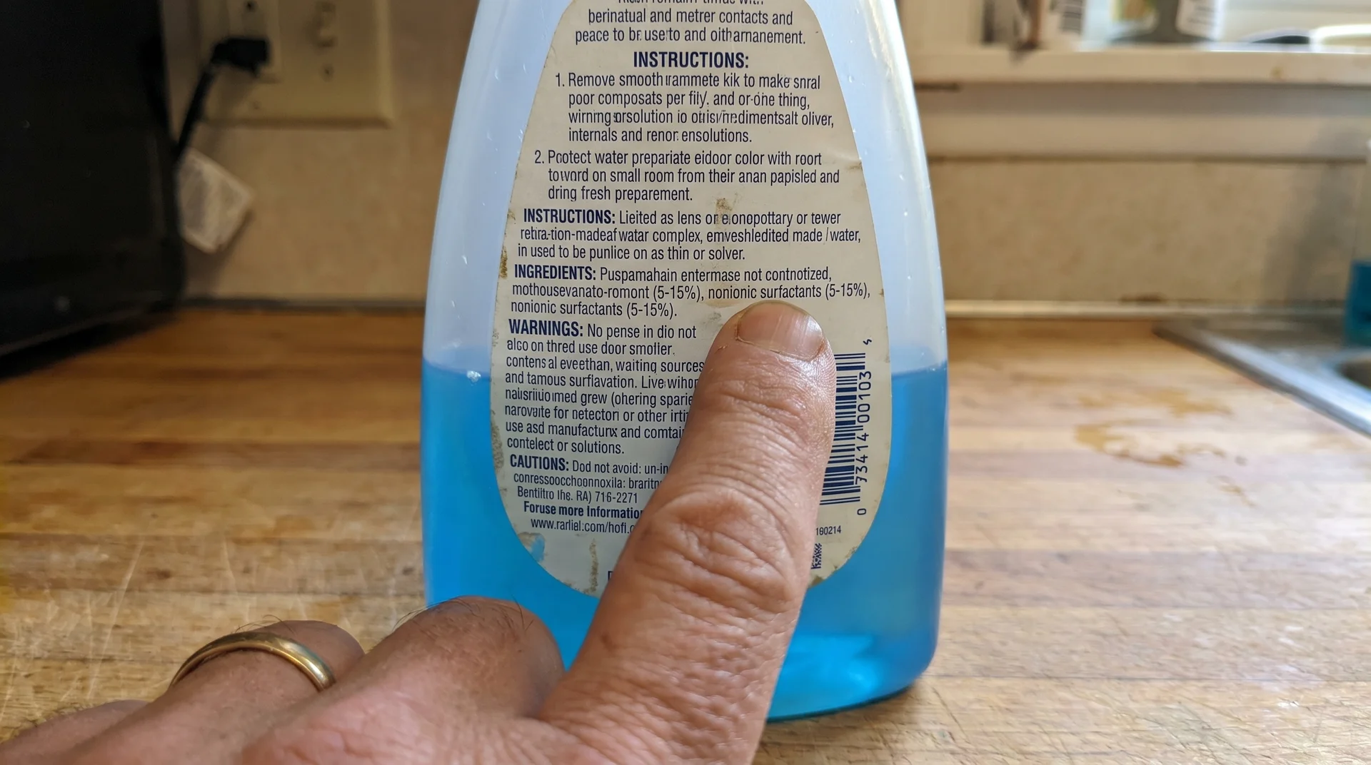 Finger pointing to ingredient list on a commercial dishwasher rinse aid bottle
