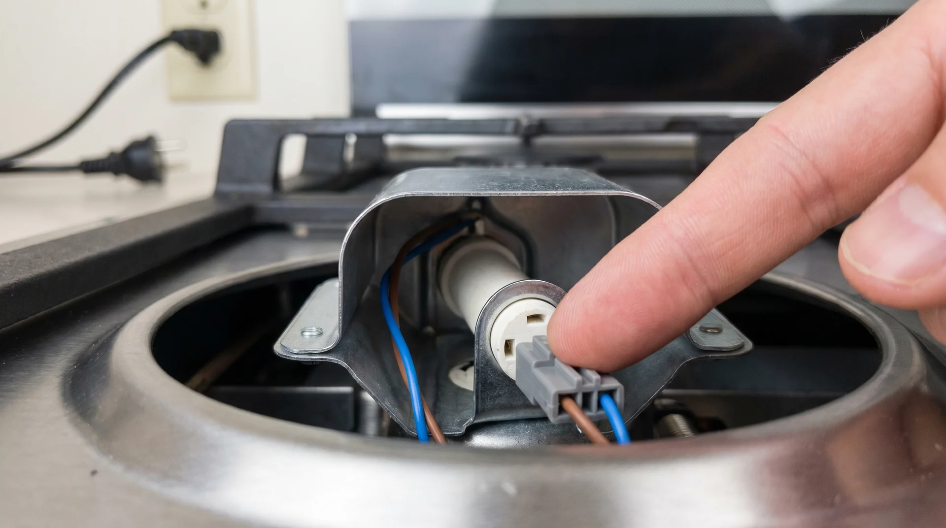 Finger pressing wire connector back onto gas stove igniter electrode base, burner area open above