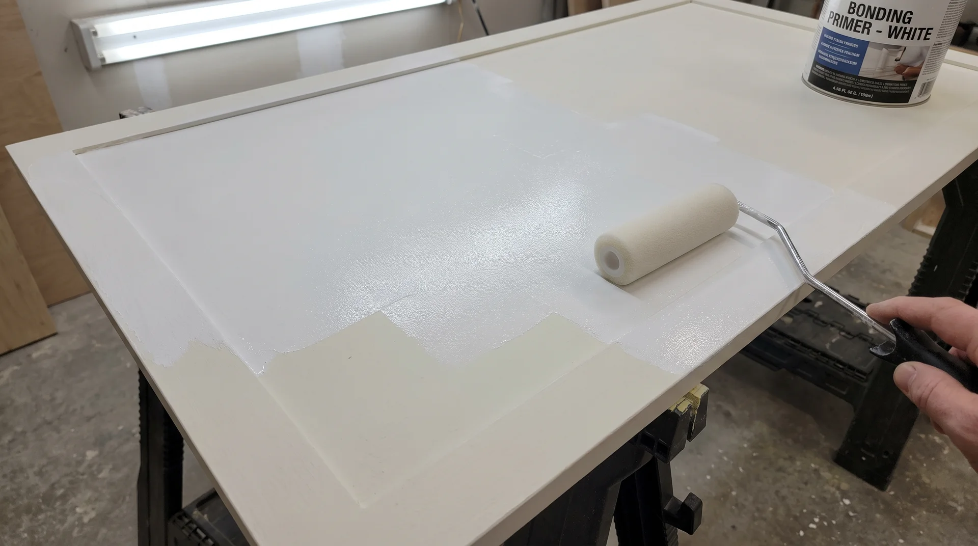 Foam roller applying thin coat of bonding primer to already-painted cabinet door