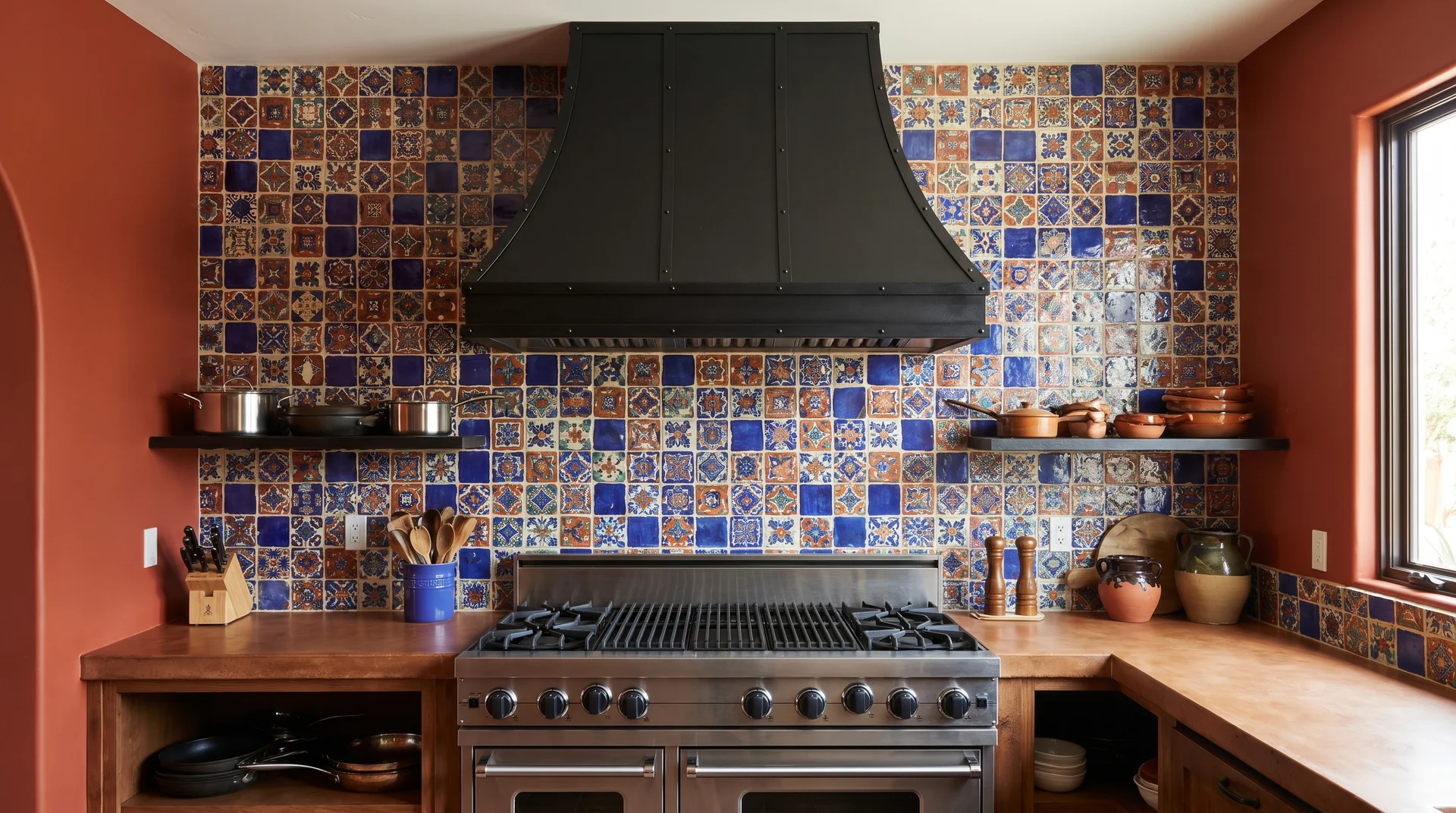 Full height hand-painted Talavera backsplash tile in cobalt and terracotta behind a kitchen range