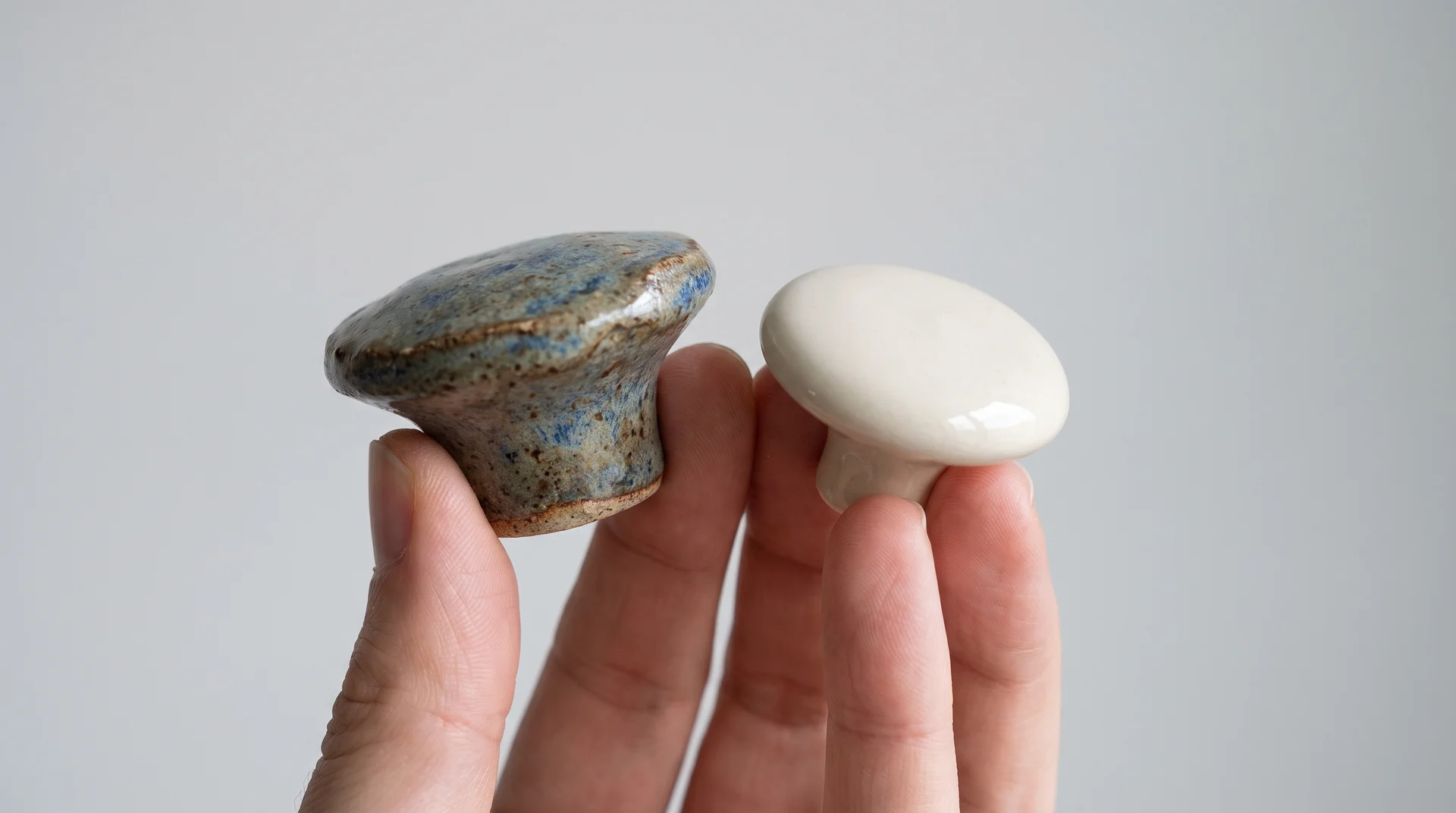 Handmade ceramic knob with glaze variation beside uniform production ceramic knob showing quality and weight difference