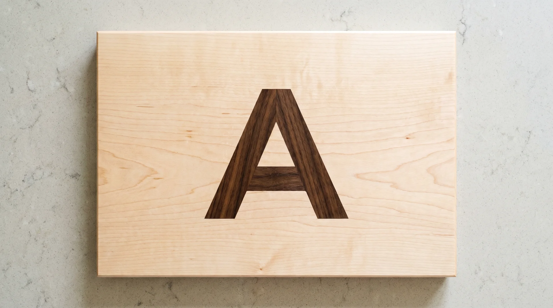 Maple cutting board with dark walnut carved monogram letter inlaid flush into the surface