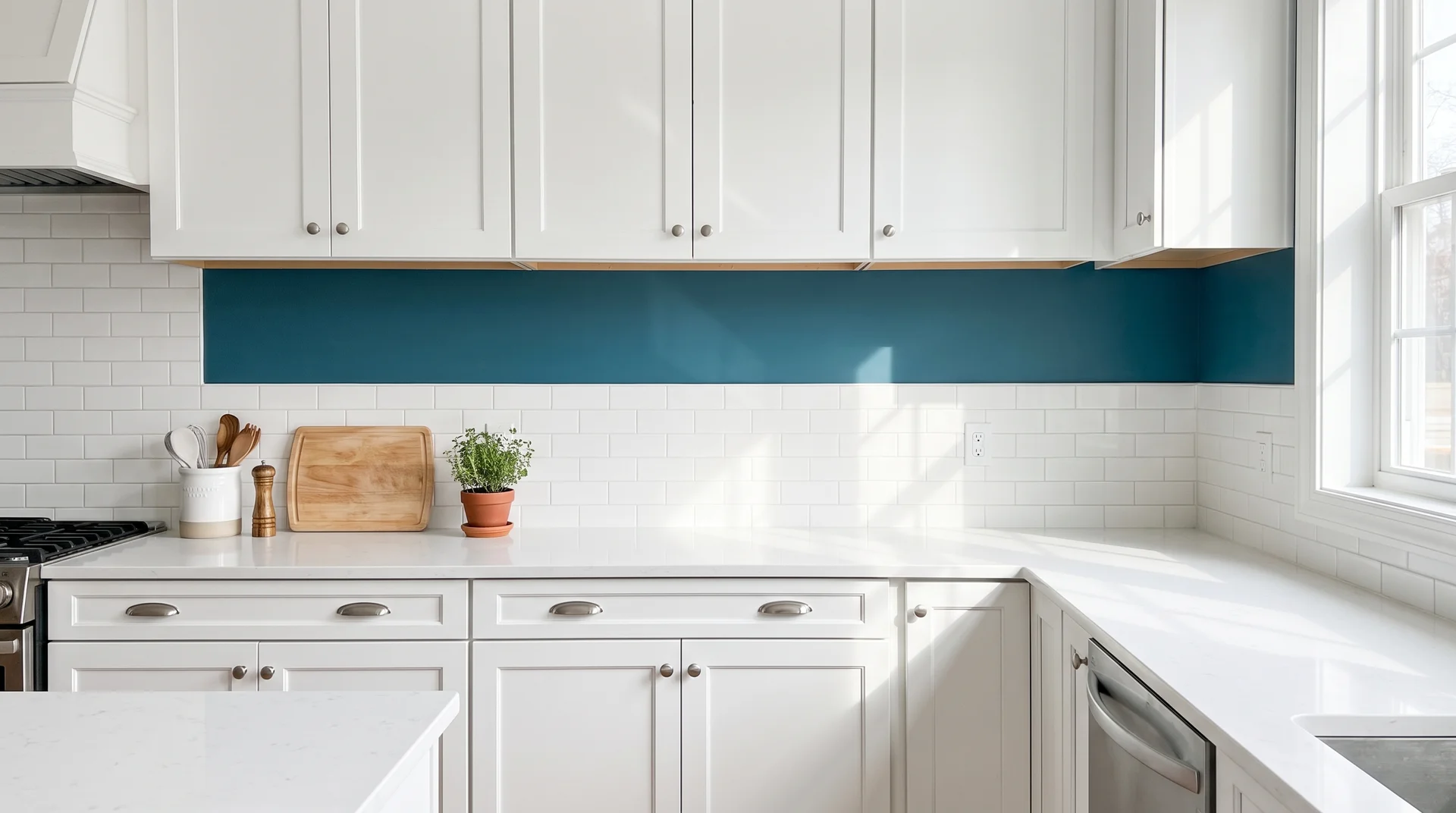 Narrow strip of deep teal wall paint between white backsplash tile and white upper cabinets in a real kitchen