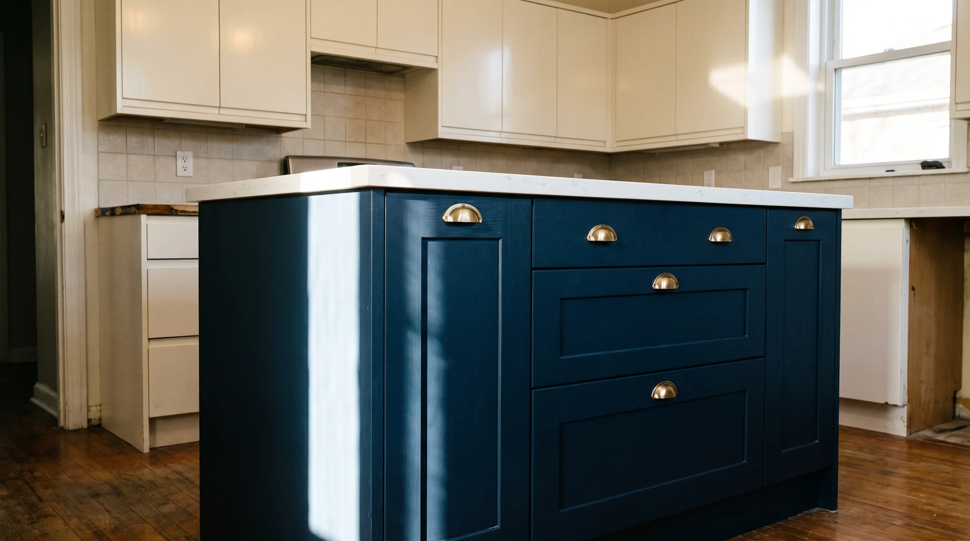 Navy two-tone kitchen island base against cream upper cabinets showing correct sheen-matched finishes with brass hardware