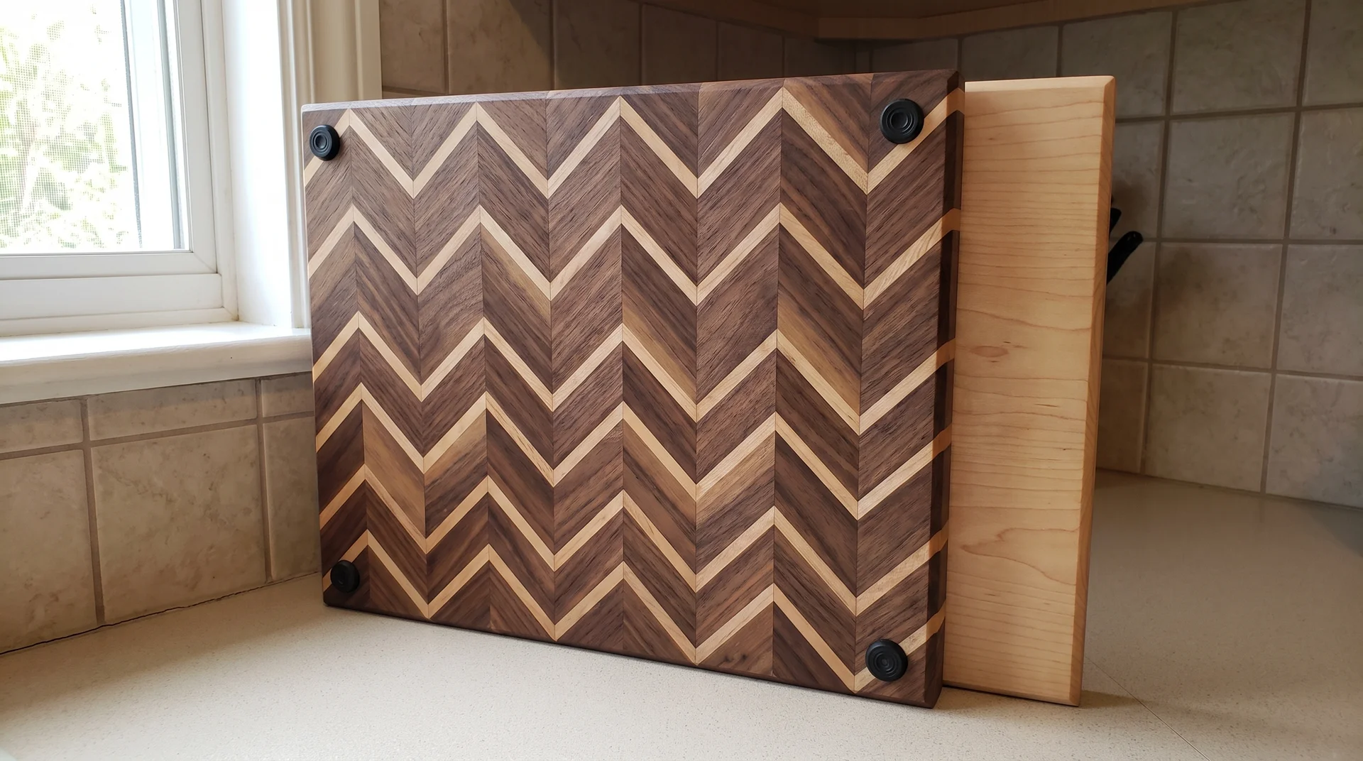 Reversible cutting board propped to show decorative chevron face on one side and plain maple cutting surface on other