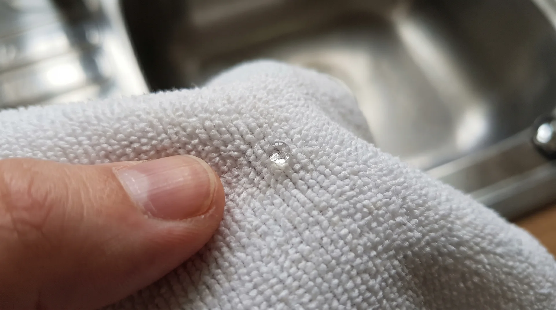 Single drop of mineral oil on a microfiber cloth against a stainless steel surface