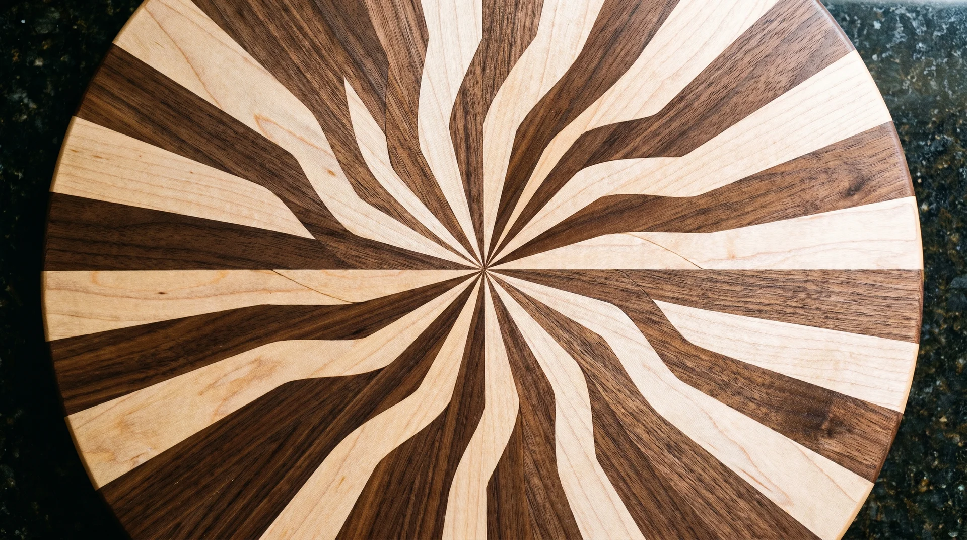Sunburst pinwheel cutting board with walnut and maple strips radiating outward from center point