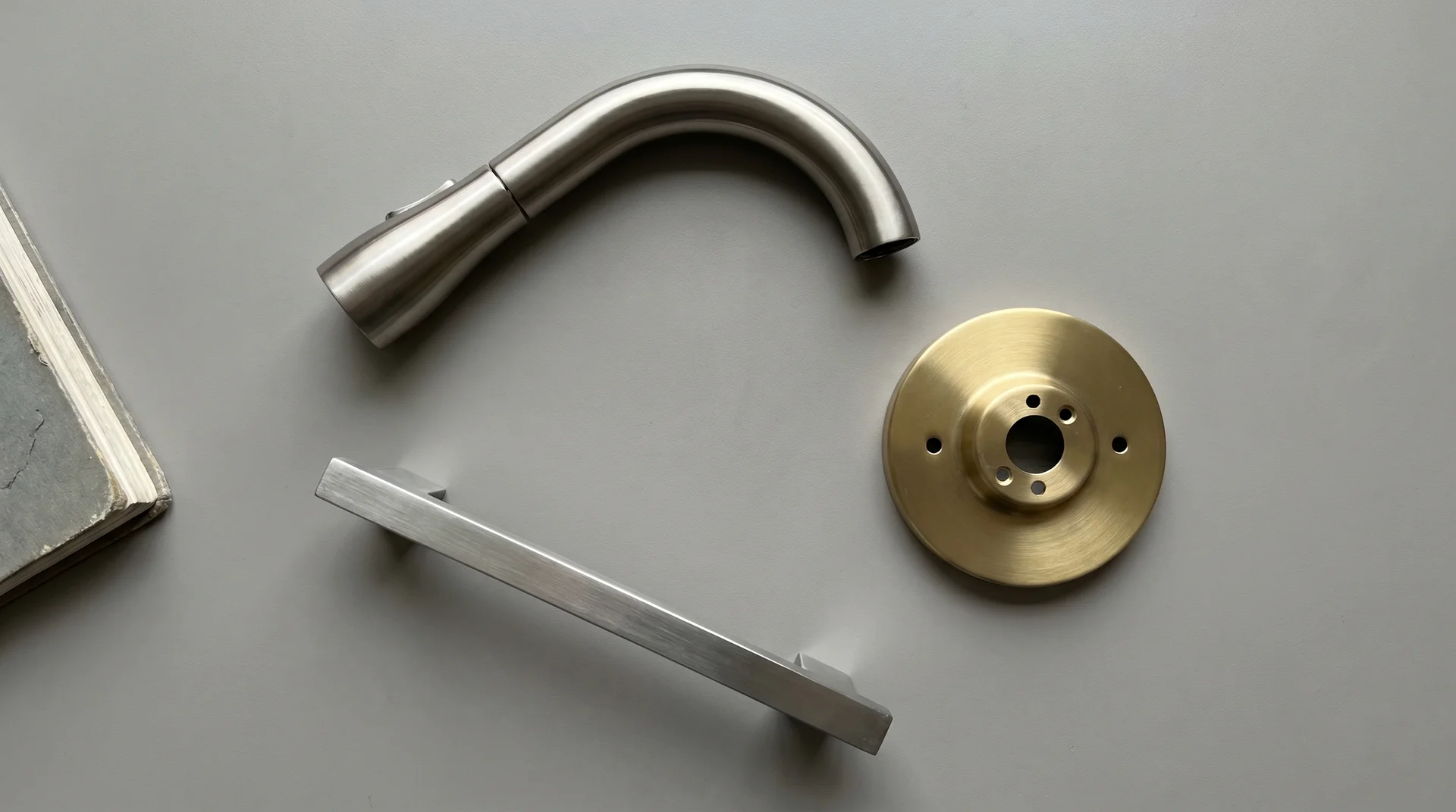 Three fixed kitchen metals — faucet, light fixture, and appliance handle — shown together for finish reference
