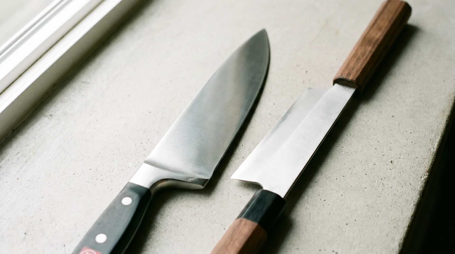 Two chef's knives side by side showing the visual difference between a German and Japanese blade profile