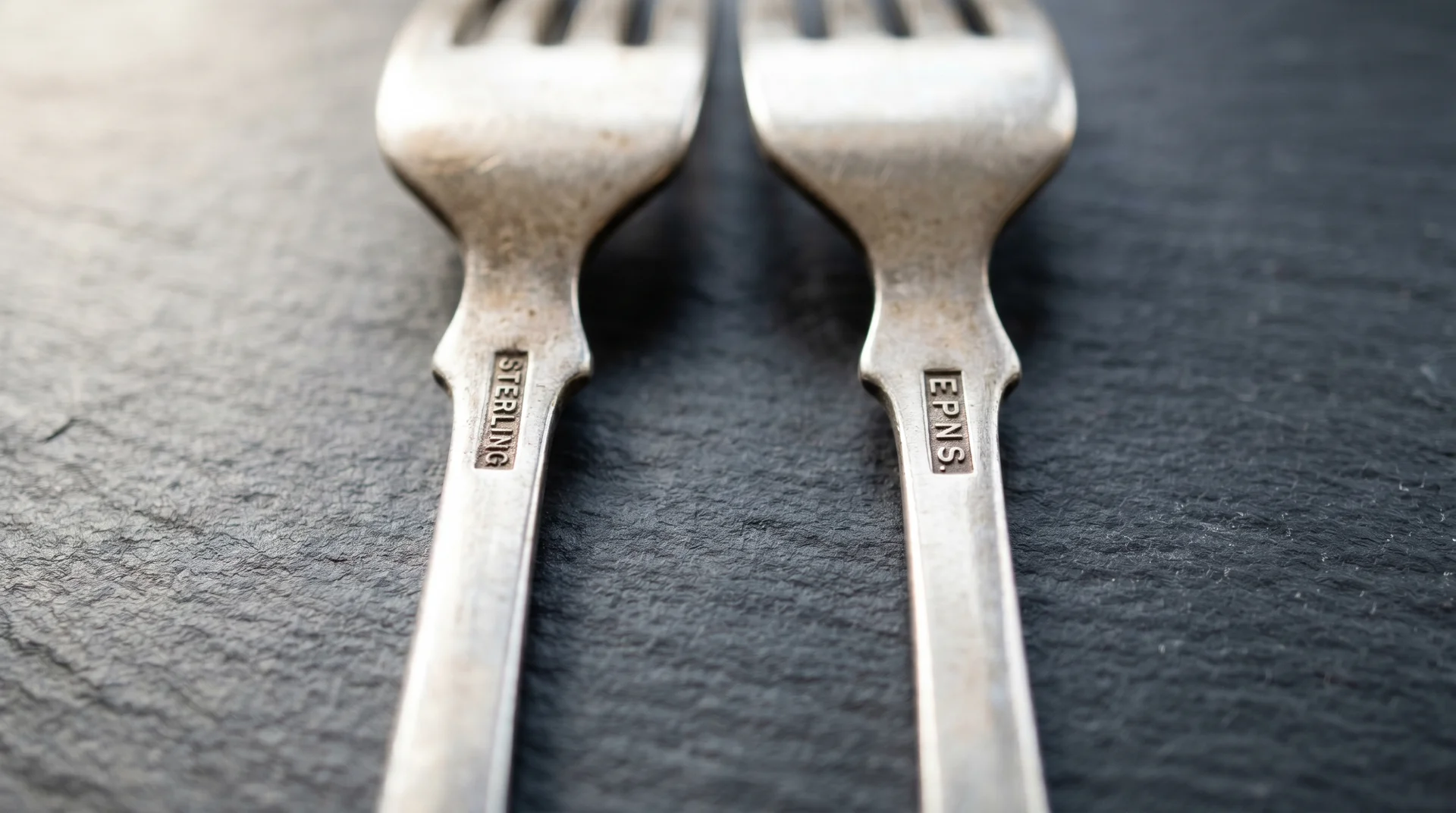 Two fork handles side by side showing Sterling and EPNS stamps for silver identification