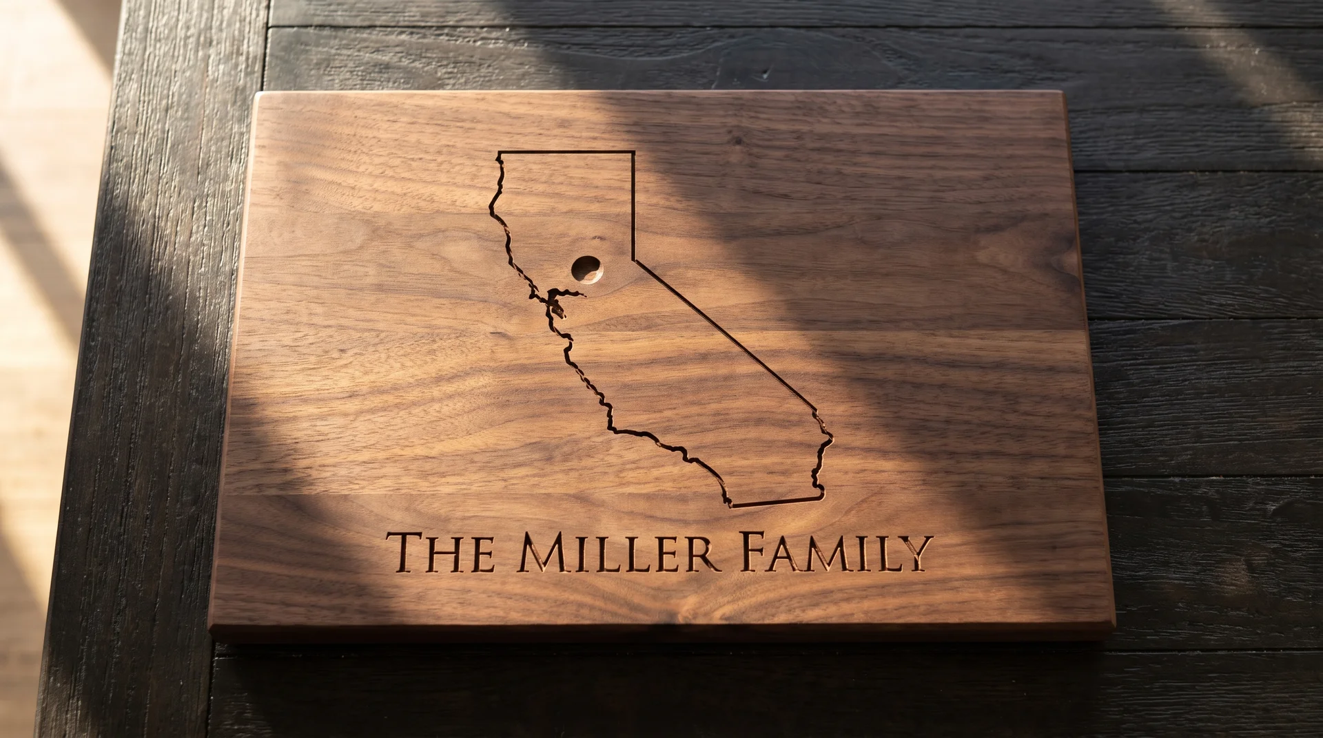 Walnut board with a clean state outline, location dot, and family name beneath, raking sidelight