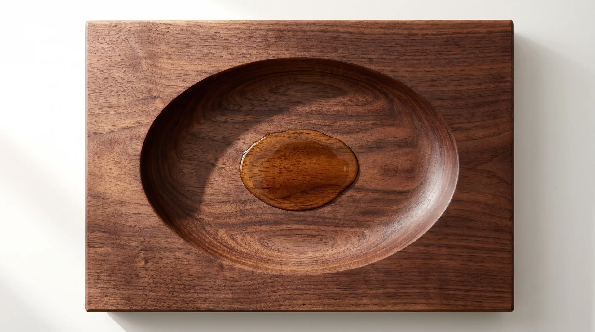 Walnut cutting board with large central oval juice well depression showing liquid pooled at the source